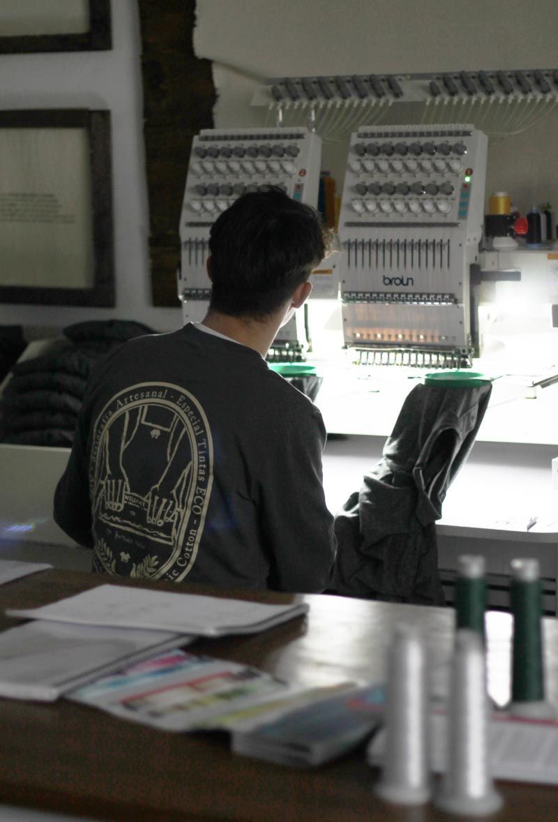 Persona trabajando en una estación de trabajo electrónica bien iluminada con placas de circuitos y herramientas.