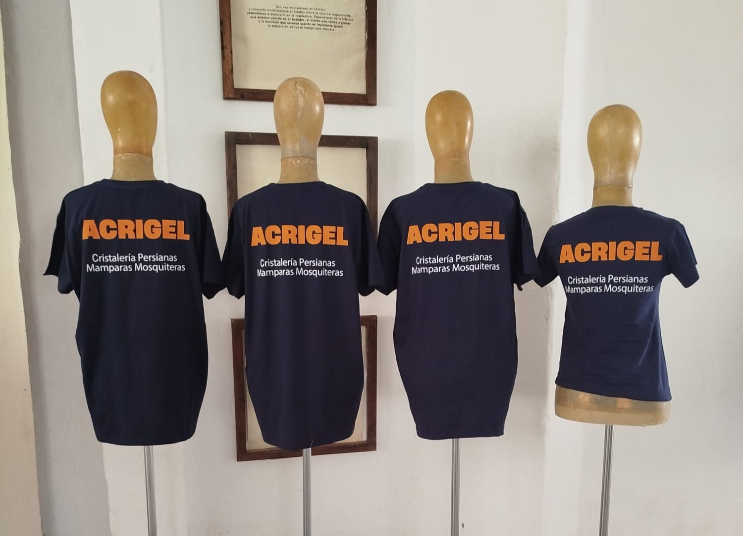 Cuatro maniquíes con camisetas AGRIBEL azul marino con letras naranjas, expuestos en el interior.