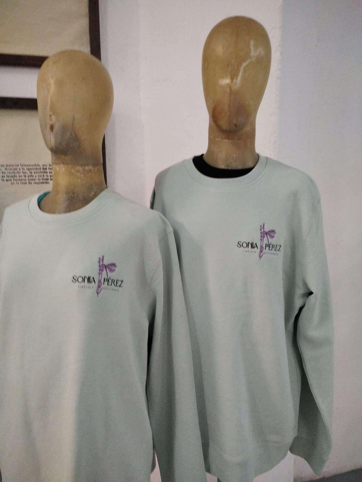 Dos maniquíes con sudaderas de color gris claro con un pequeño logotipo en el pecho.