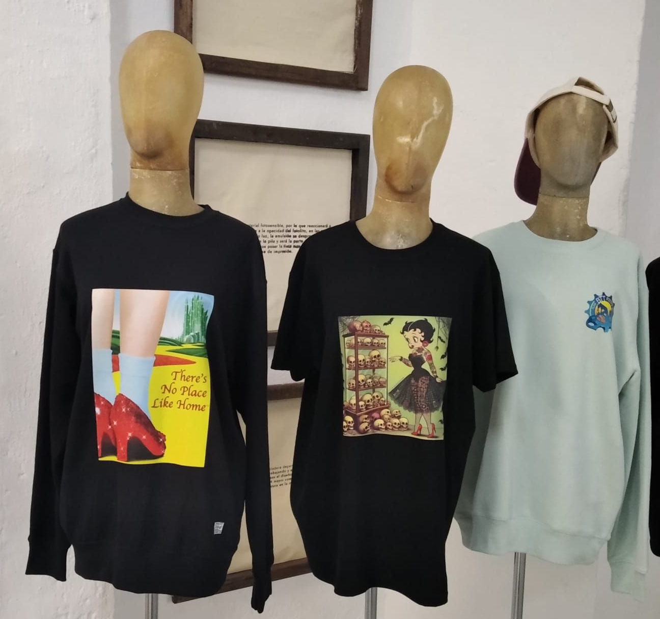 Tres maniquíes que lucen camisetas estampadas en negro y menta, expuestos en el interior.