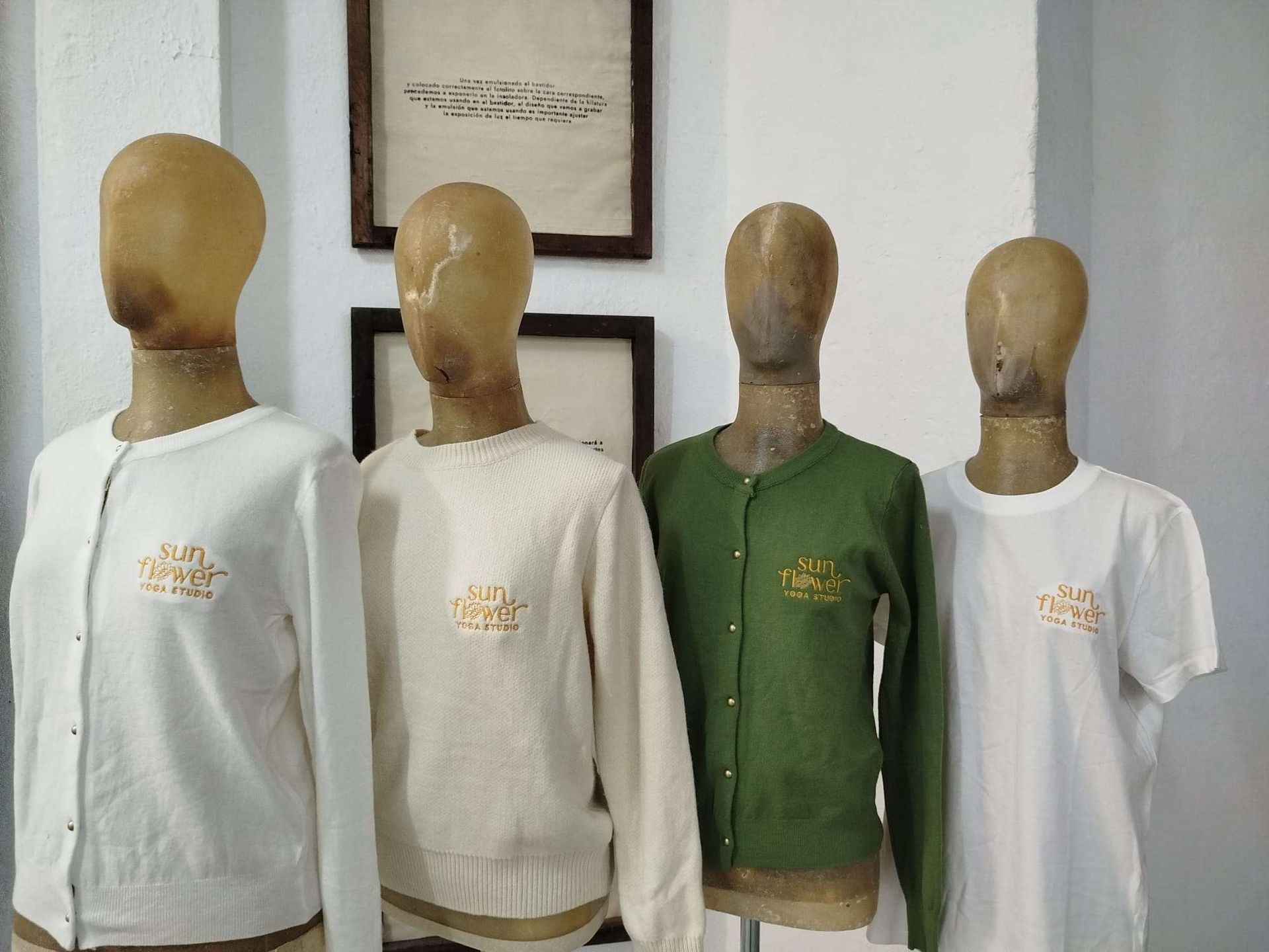 Cuatro torsos de maniquí con camisas blancas y verdes expuestos en el interior, apoyados contra una pared.