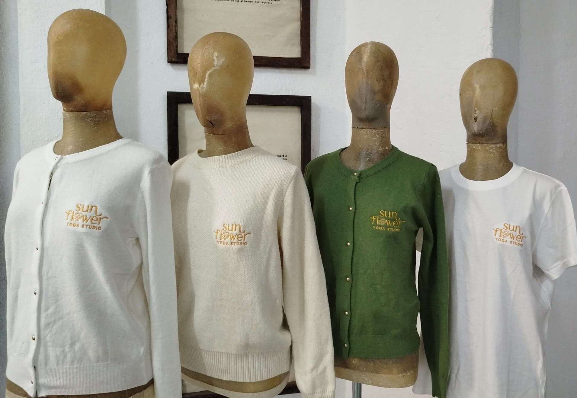 Cuatro torsos de maniquí con camisas blancas y verdes expuestos en el interior, apoyados contra una pared.