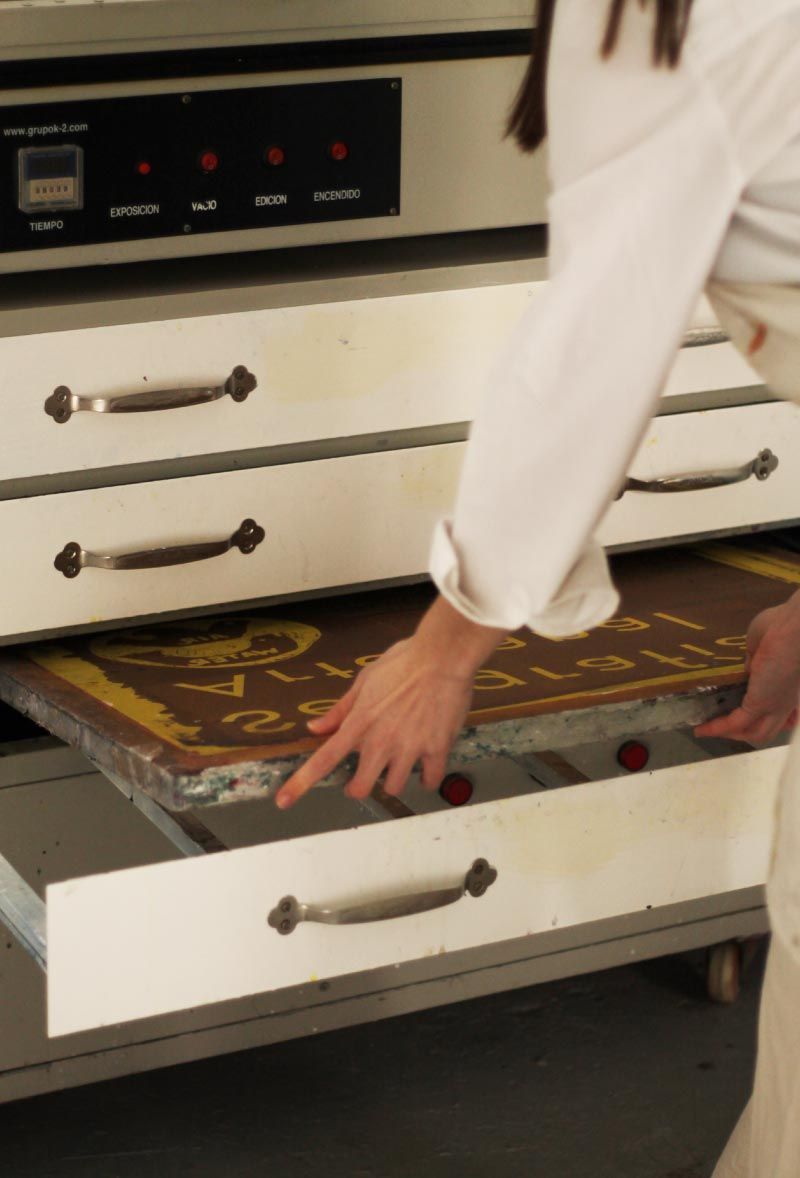 Una mano se introduce en un cajón de cocina blanco abierto con un revestimiento decorativo.