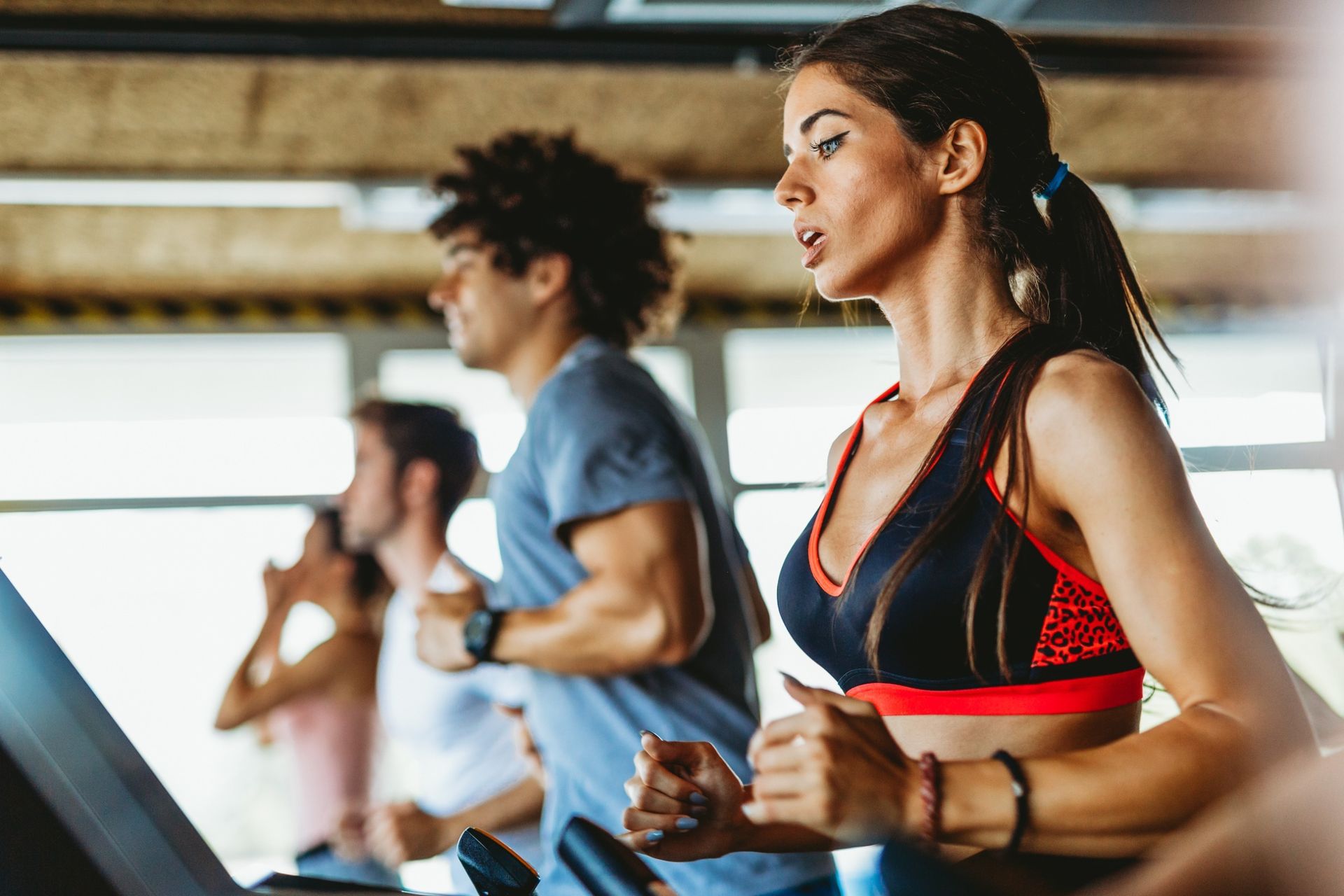Un grupo de personas corre en cintas de correr en un gimnasio.
