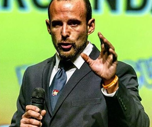 Un hombre con traje y corbata sostiene un micrófono.