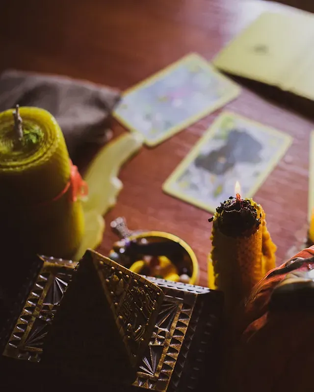 Una mesa con velas y cartas del tarot sobre ella.