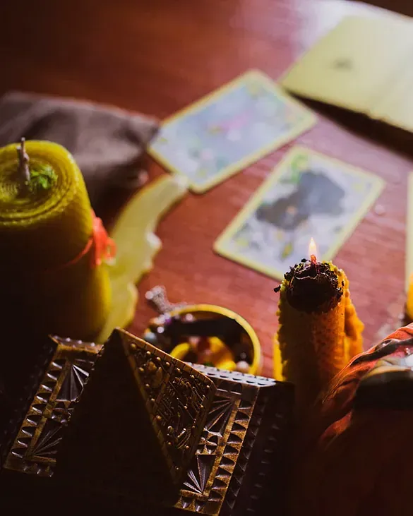 Una mesa con velas y cartas del tarot sobre ella.