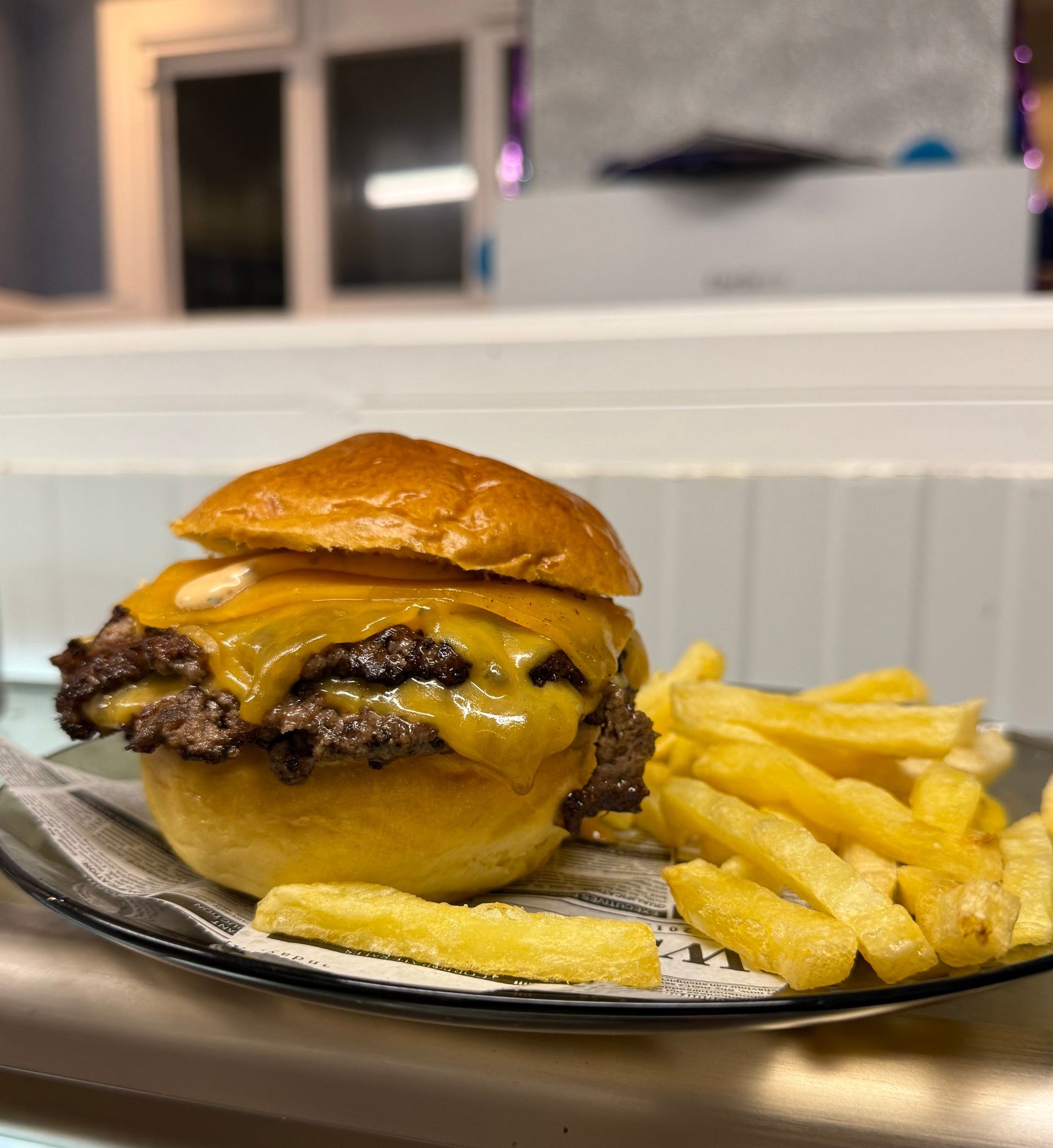 Hamburguesa doble con queso, tocino y papas fritas. La hamburguesa lleva pan dorado, queso derretido y tocino crujiente.