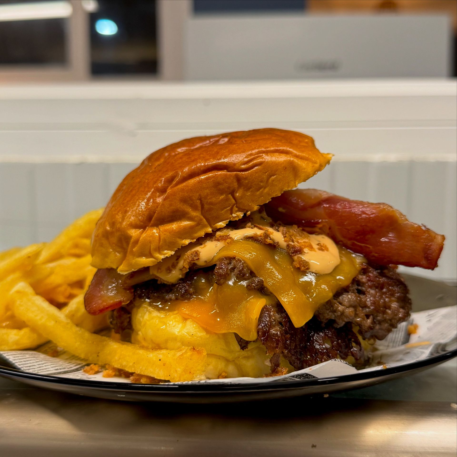 Hamburguesa doble con queso, tocino y papas fritas. La hamburguesa lleva pan dorado, queso derretido y tocino crujiente.