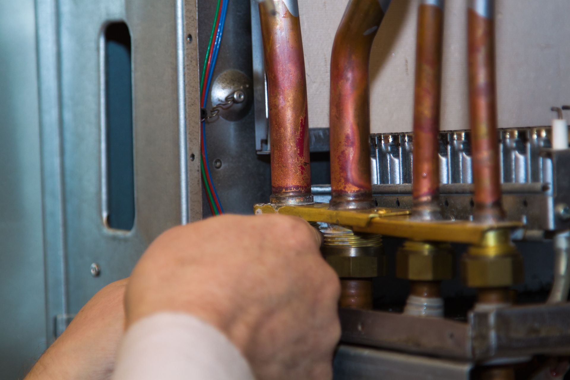 Technicien ajustant les tuyaux de cuivre à l'intérieur d'une chaudière ou d'un appareil de chauffage.