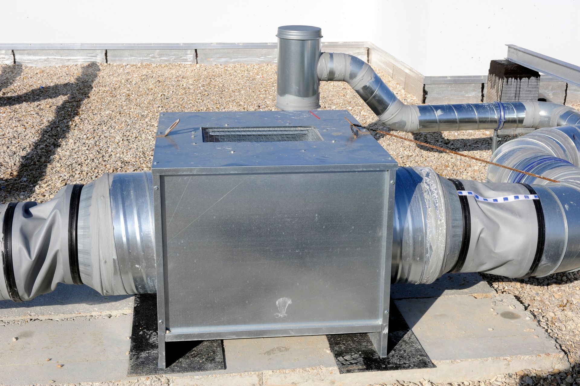 Conduits de ventilation en toiture avec boîtier métallique et tuyaux d'évacuation flexibles et isolés.
