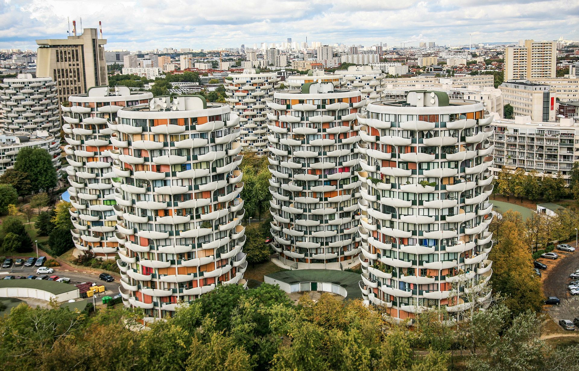 Immeubles d'appartements modernes avec balcons incurvés dans un quartier urbain verdoyant.