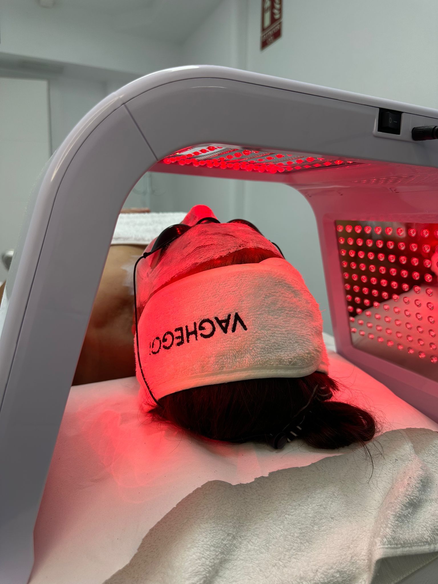 Persona recibiendo un tratamiento facial. Alguien con una toallita blanca limpia el rostro de la mujer mientras ella se relaja con los ojos cerrados.
