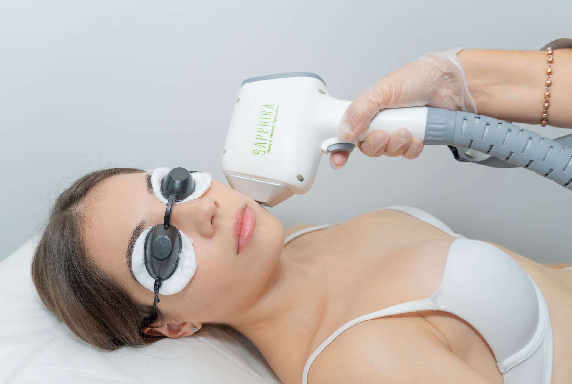 Mujer recibiendo tratamiento de depilación láser en la cara, usando gafas protectoras, en un entorno clínico.