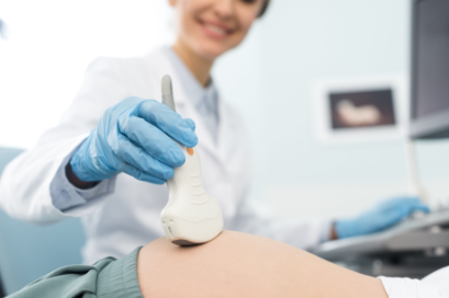 Profesional médico utilizando una sonda de ultrasonido en el abdomen de un paciente.