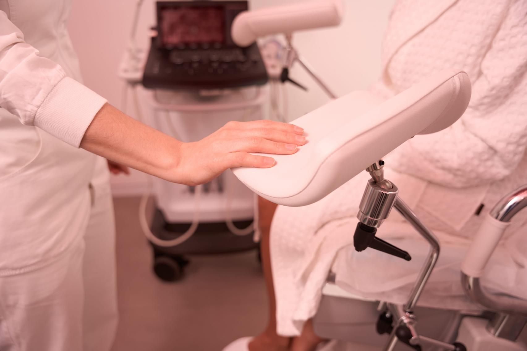Persona ajustando una silla médica blanca en una sala de consulta.