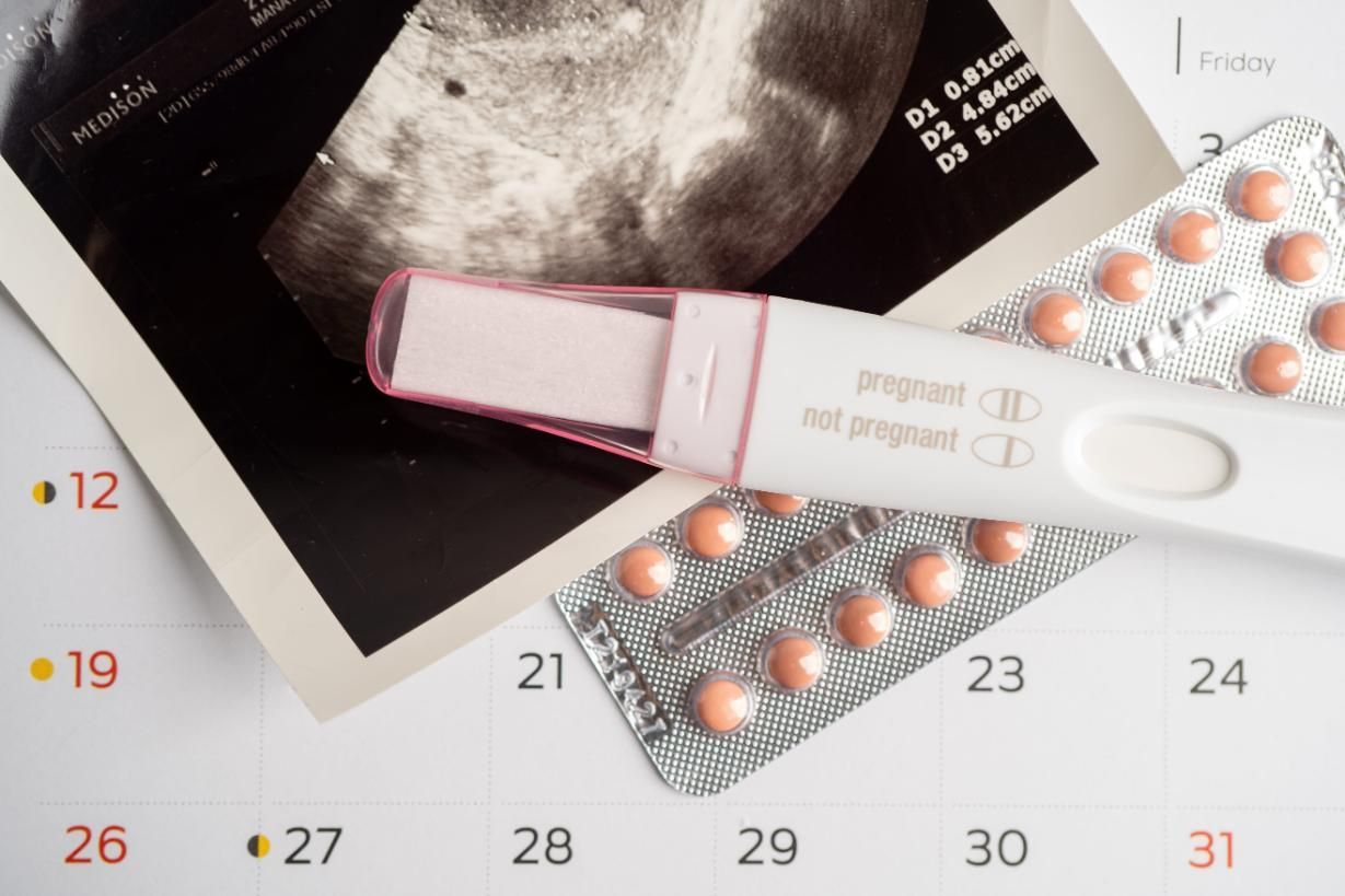 Fotografía de ultrasonido y dos paquetes de pastillas rosas y blancas en una página de calendario.