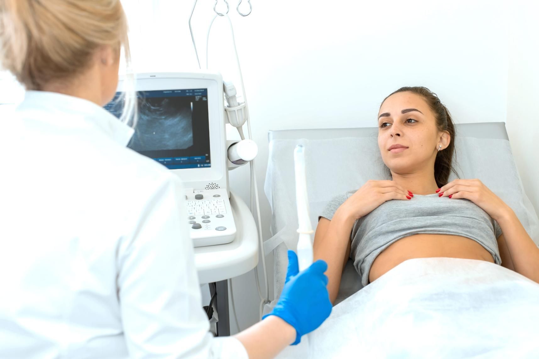 Médico realizando una ecografía a un paciente acostado en una camilla de exploración.
