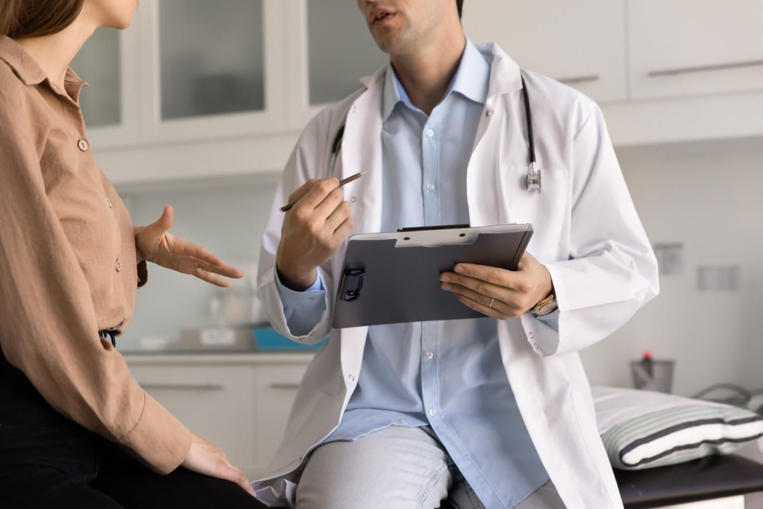 Un médico comenta sus notas con un paciente en una sala de exploración clínica.