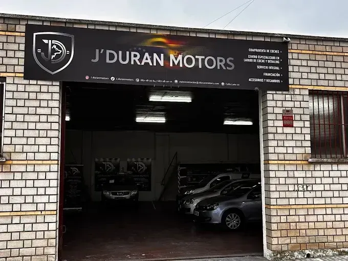 Escaparate de J'Duran Motors con una pancarta y varios coches dentro del garaje.