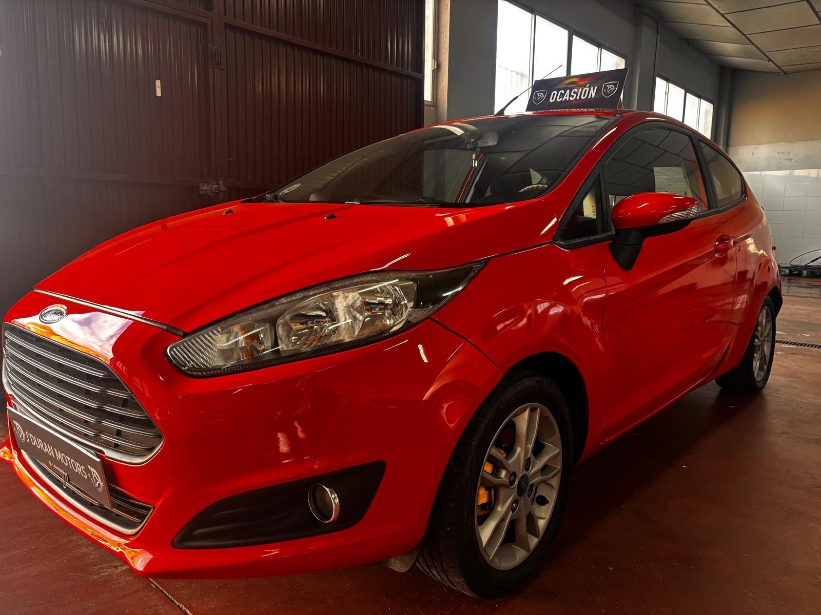 Un Ford Fiesta hatchback de color rojo brillante estacionado dentro de un garaje.
