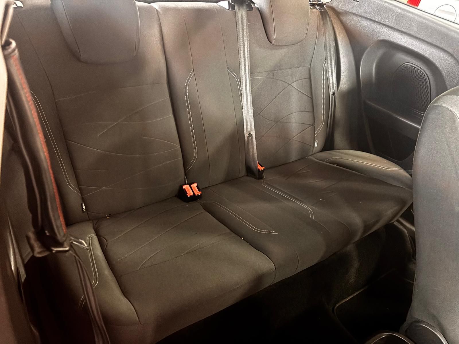 Primer plano de los asientos traseros de tela gris oscuro con cinturones de seguridad y reposacabezas integrados en el interior de un vehículo.