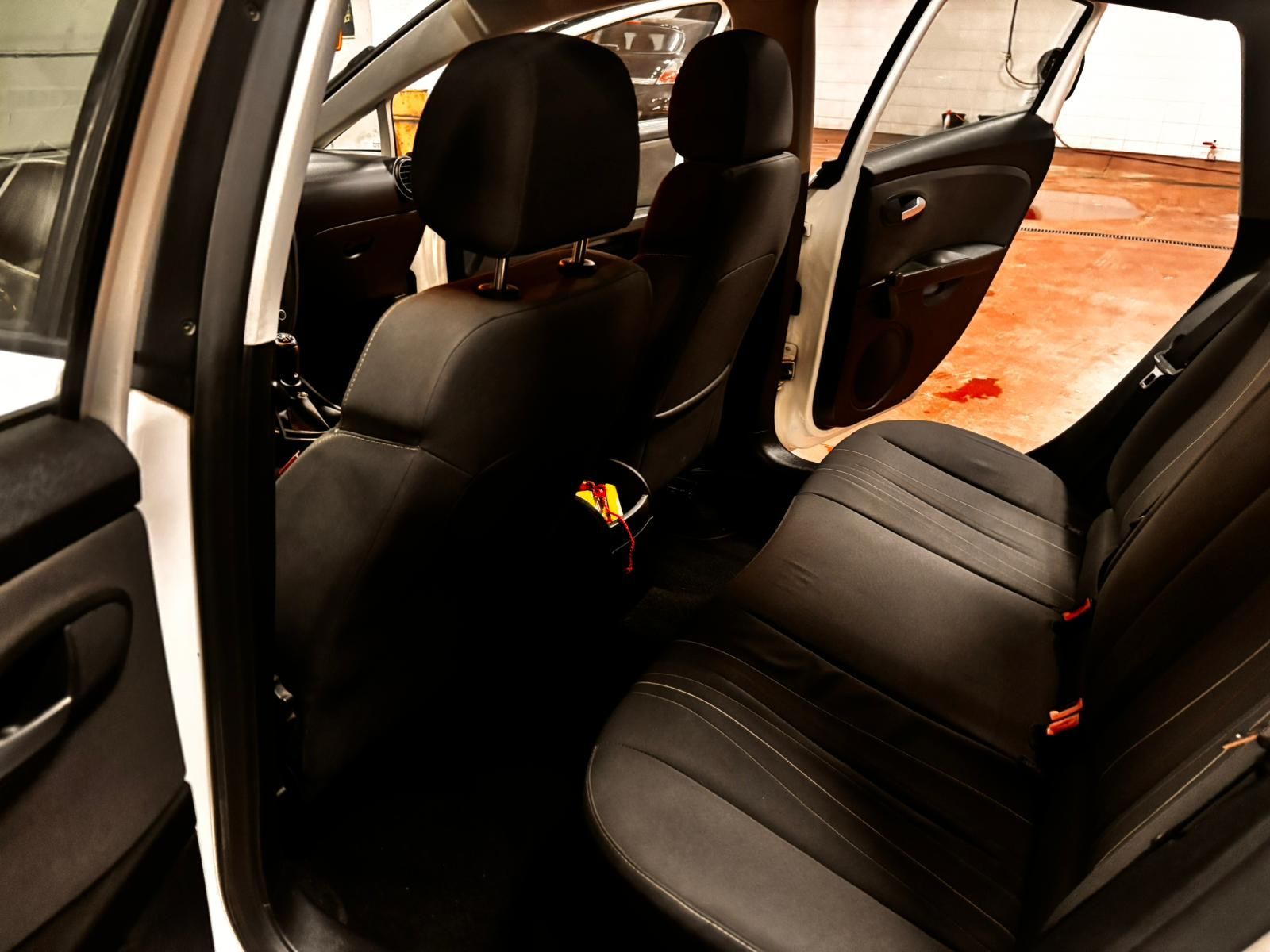 El interior del coche muestra la zona de los asientos traseros con tapicería oscura y la puerta trasera del pasajero abierta.