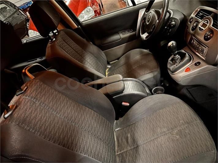 Vista interior de un automóvil con asientos de tela negra, consola central y volante visibles.