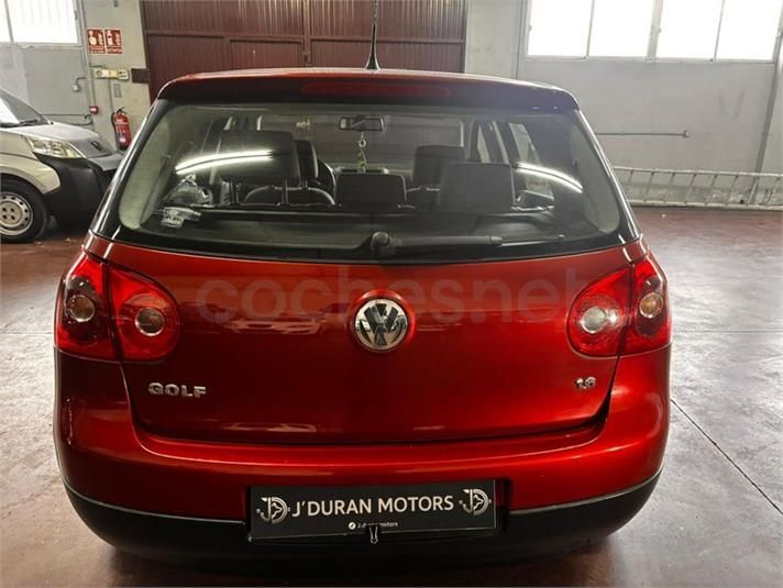 Volkswagen Golf hatchback rojo, vista trasera, estacionado en el interior, mostrando luces traseras y logotipo.