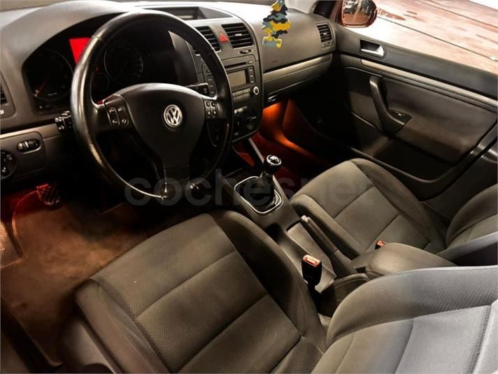 Interior de un Volkswagen Golf con tablero negro, asientos grises y volante.