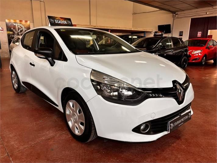 Coche Renault Clio de color blanco en una sala de exposición, aparcado delante de otros vehículos.
