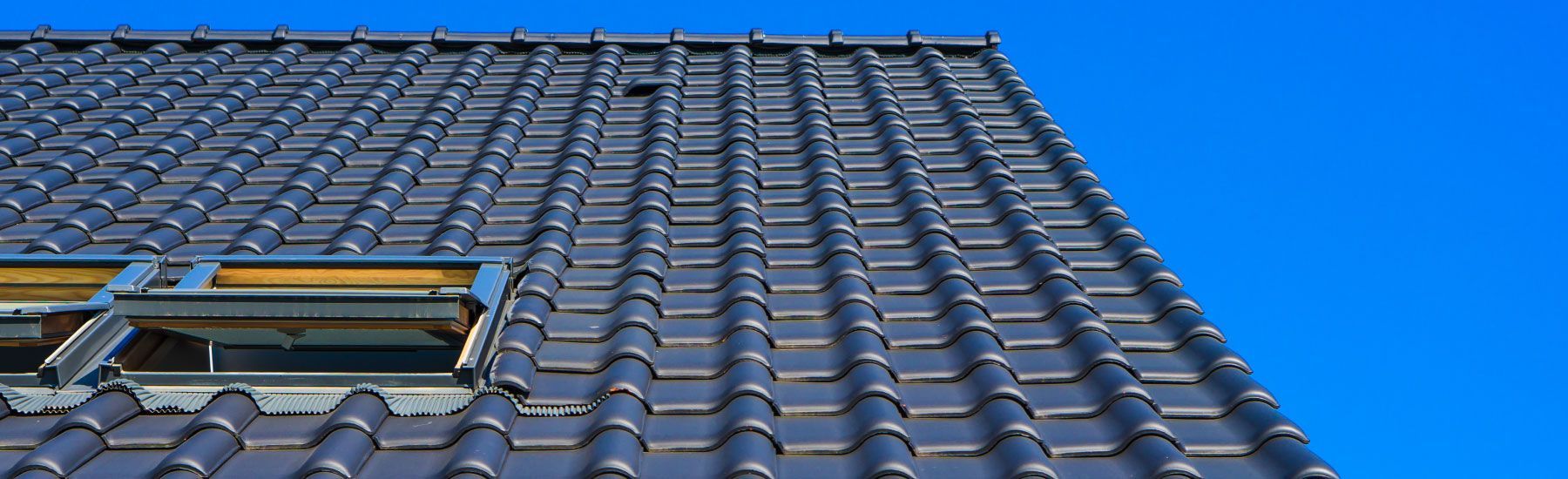 Ein Dach mit einem Fenster und einem blauen Himmel im Hintergrund