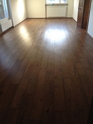 Ein Wohnzimmer mit Holzboden und Fenster.