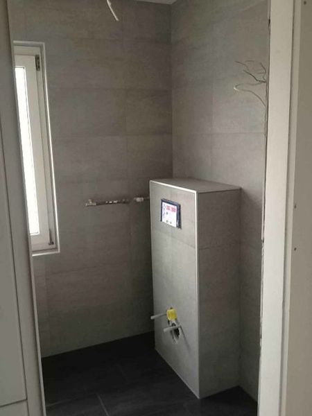 Ein Badezimmer mit Ecktoilette und Fenster.