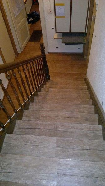 Eine Holztreppe mit Holzgeländer, die zu einem Flur führt.