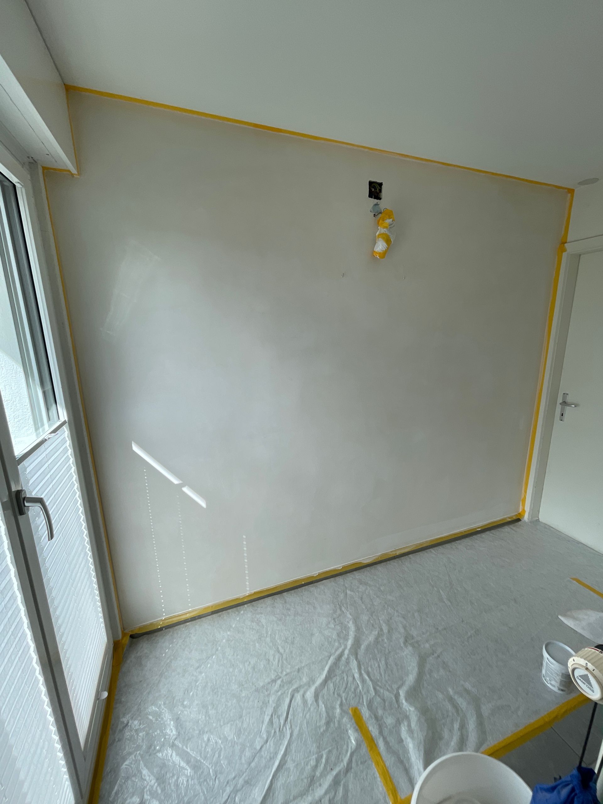 Ein Raum mit einer weißen Wand und einer weißen Plane auf dem Boden.