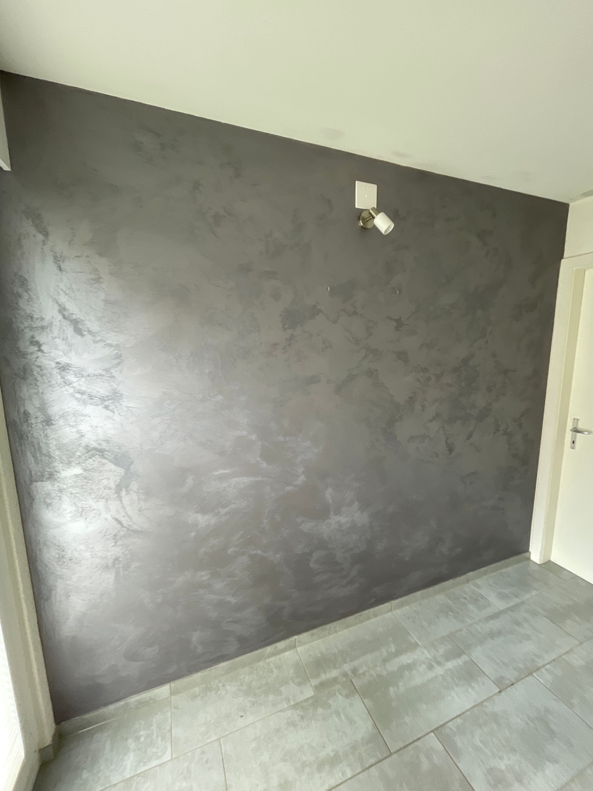 Ein Raum mit einer grauen Wand und einer weißen Tür.
