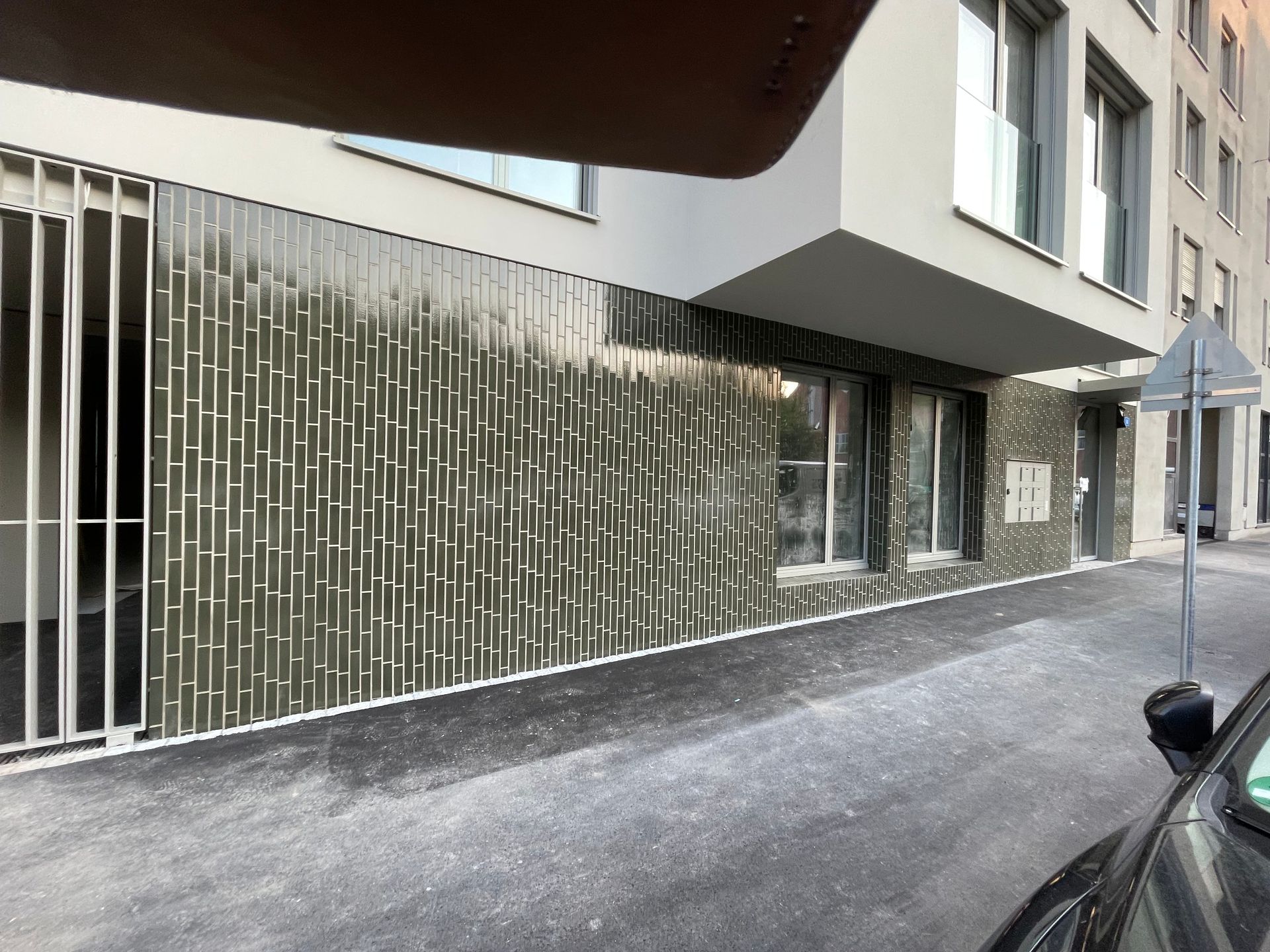 Ein Auto ist vor einem Gebäude geparkt, das von einem Zaun umgeben ist.