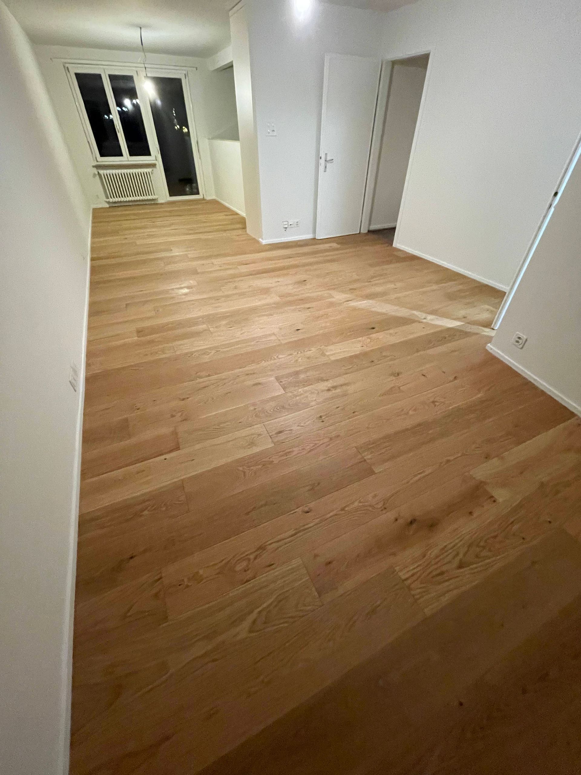 Ein Wohnzimmer mit Holzboden und weißen Wänden.