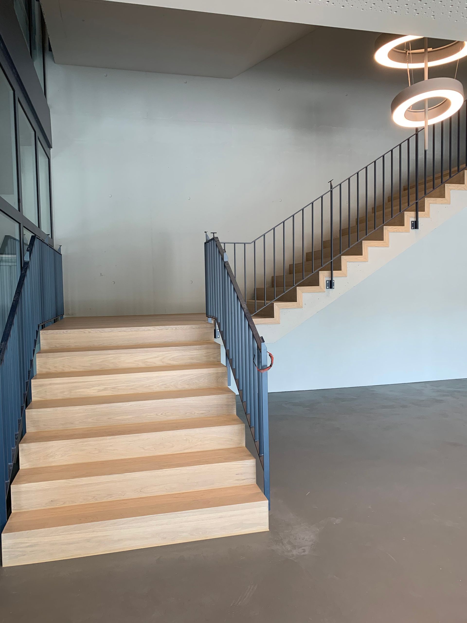 Eine Holztreppe mit einem blauen Geländer in einem leeren Raum.