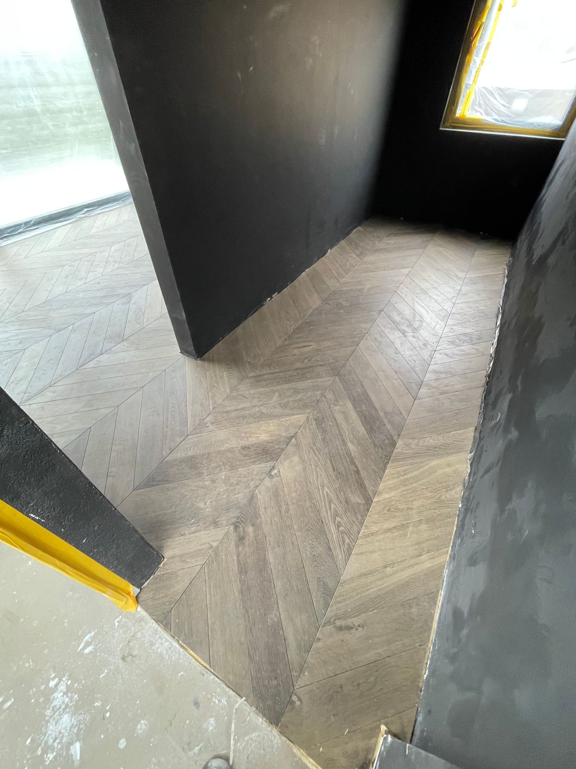 Ein Raum mit Holzboden und schwarzer Wand.