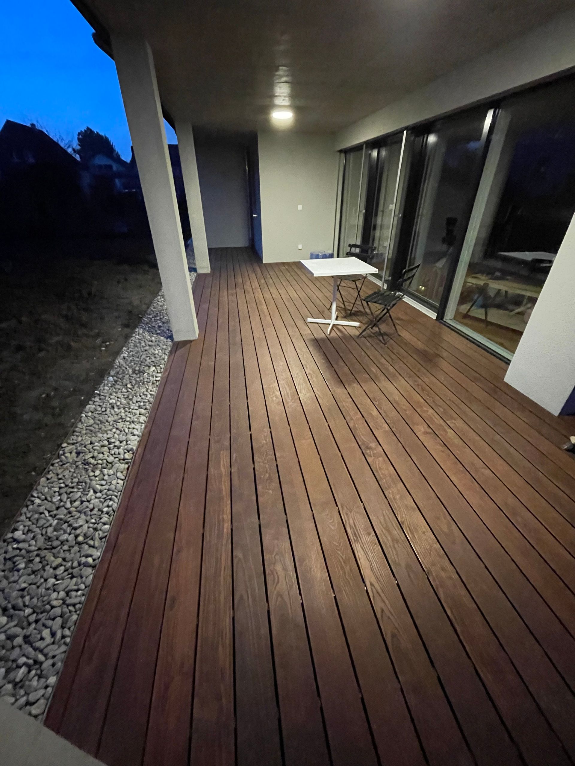 Eine Holzterrasse mit Tisch und Stühlen darauf