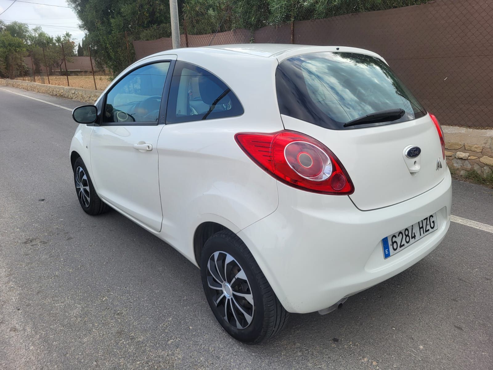 Un Ford Ka hatchback blanco estacionado en una carretera.