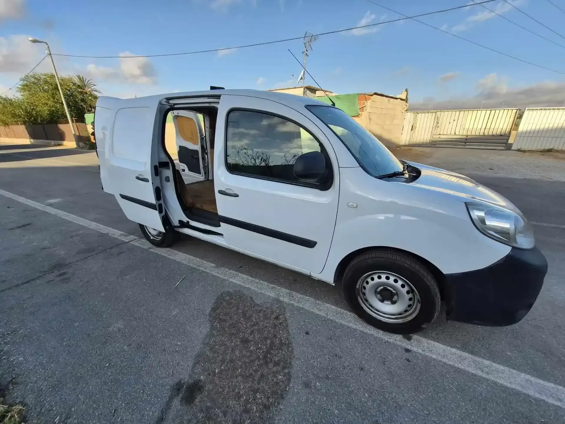 Furgoneta Renault Kangoo de color blanco con las puertas abiertas estacionada sobre asfalto.