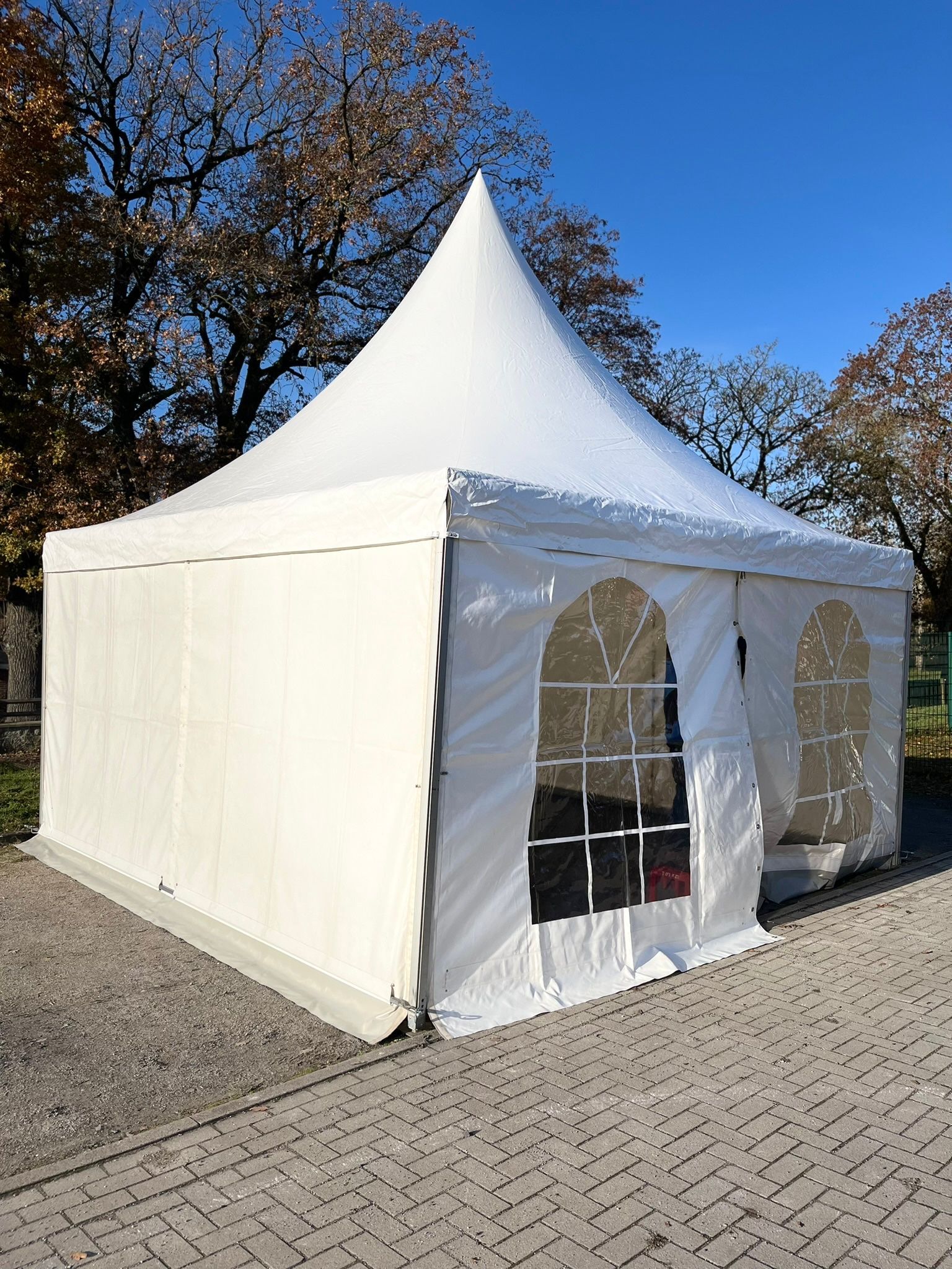 Auf einem gepflasterten Gehweg steht ein weißes Zelt.