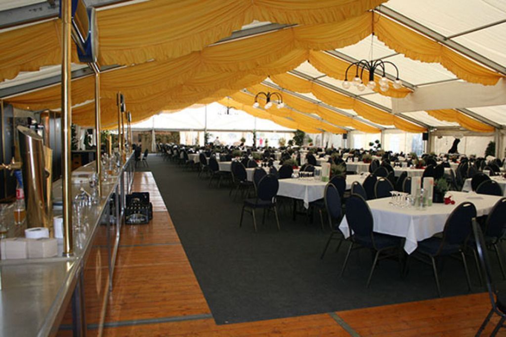 Ein großer Raum mit Tischen und Stühlen unter einem Zelt