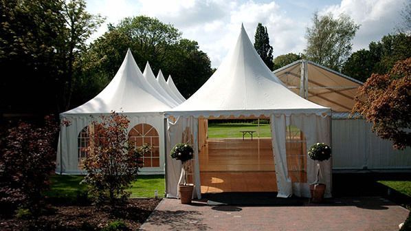 Ein großes weißes Zelt steht inmitten einer üppigen grünen Wiese.