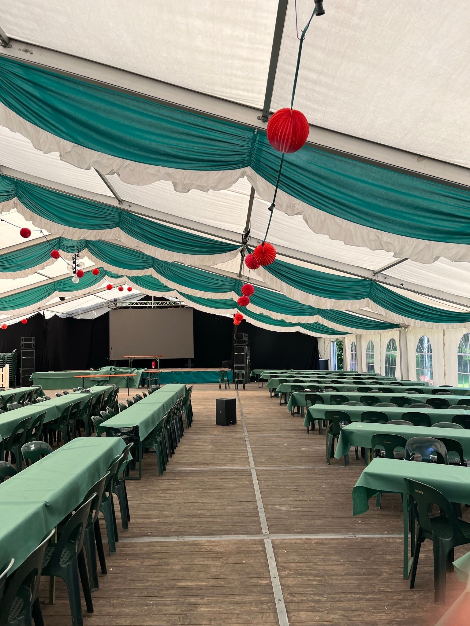 Ein großes Zelt mit Tischen und Stühlen und einer Bühne.