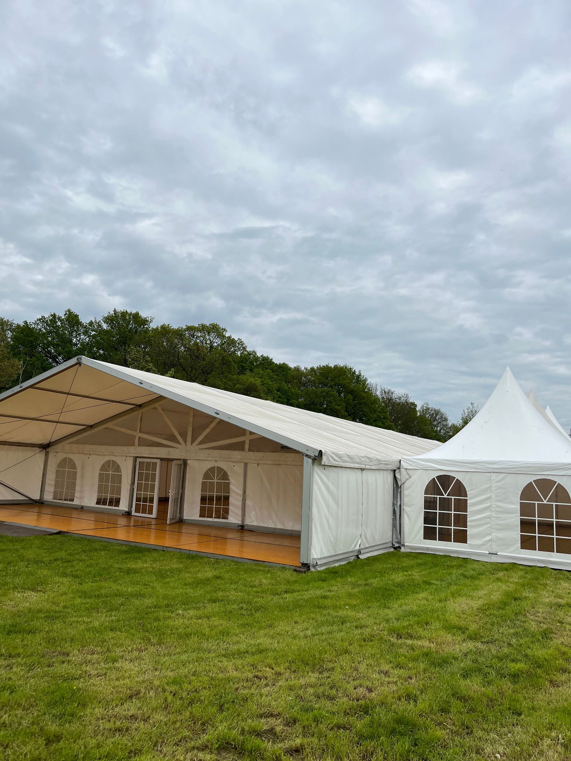 Ein großes weißes Zelt steht mitten auf einer Wiese.