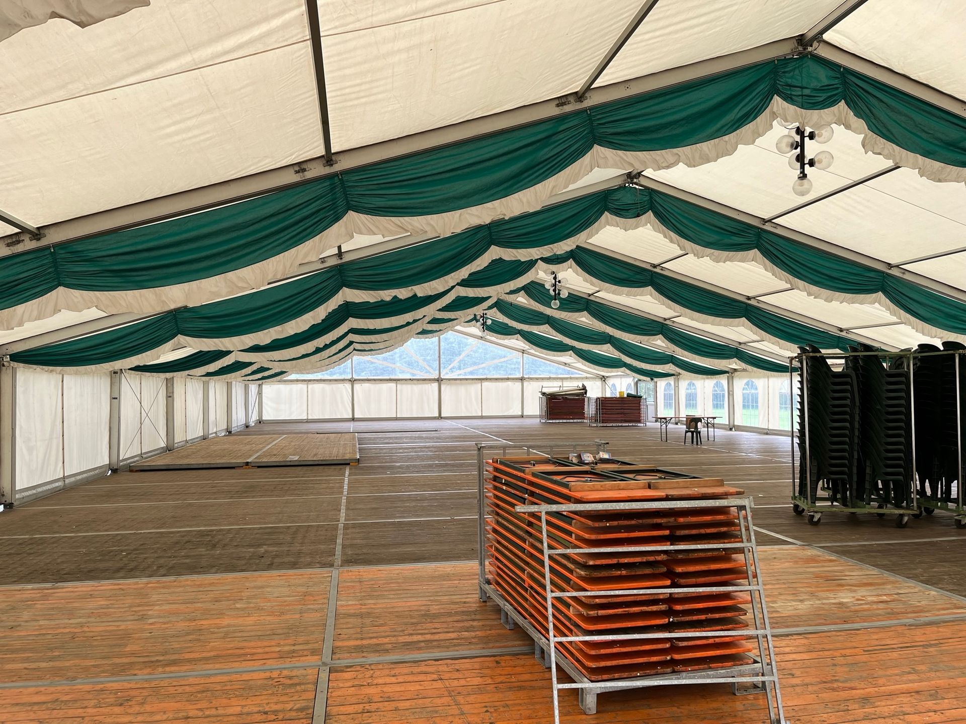 Ein großes leeres Zelt mit einem Stapel Tische und Stühle darunter.